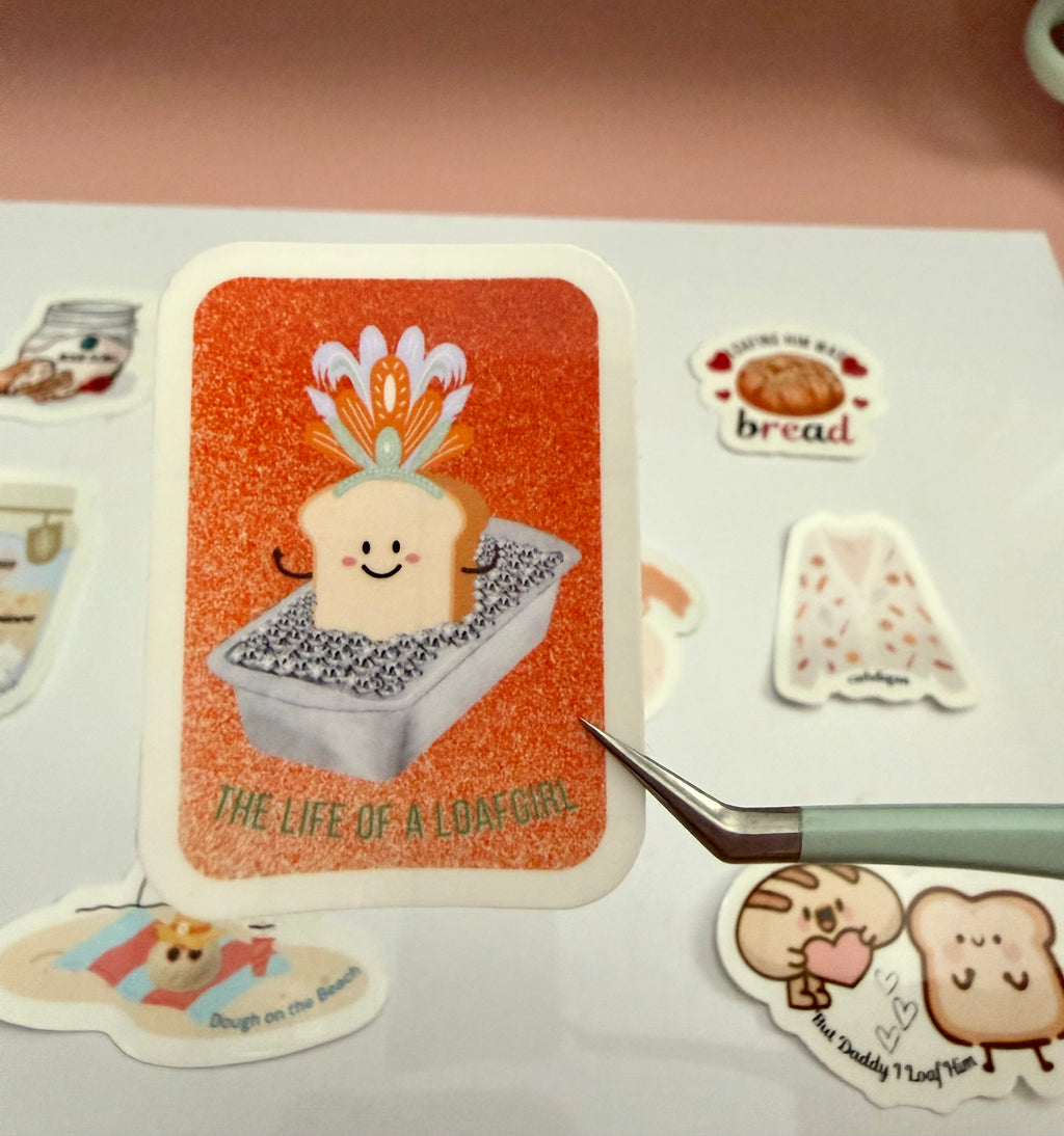 The Life of a Loafgirl sticker with a bread character on an orange background, surrounded by other similar stickers.