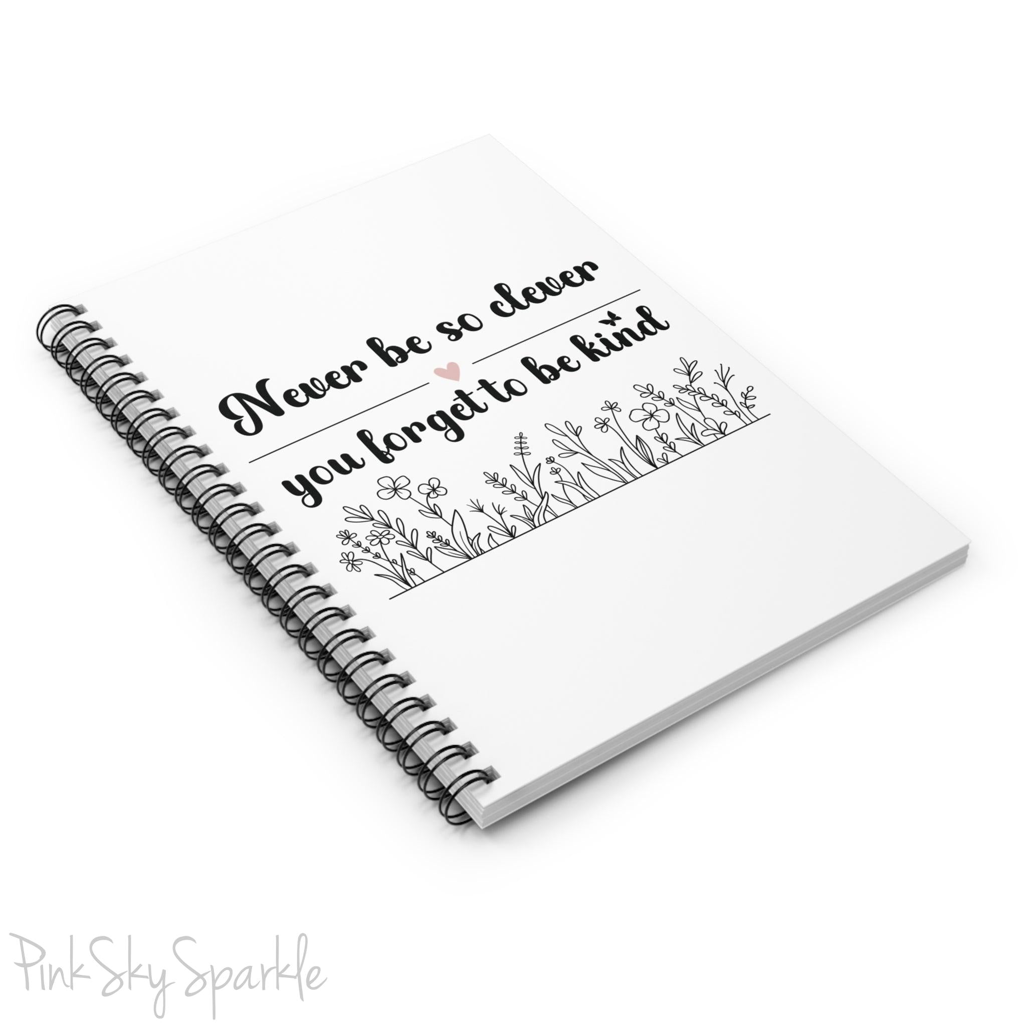 Spiral notebook with the quote "Never be so clever you forget to be kind" and flowers on it.