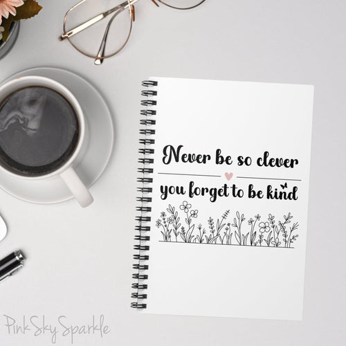 Spiral notebook with the quote "Never be so clever you forget to be kind" and flowers on it.
