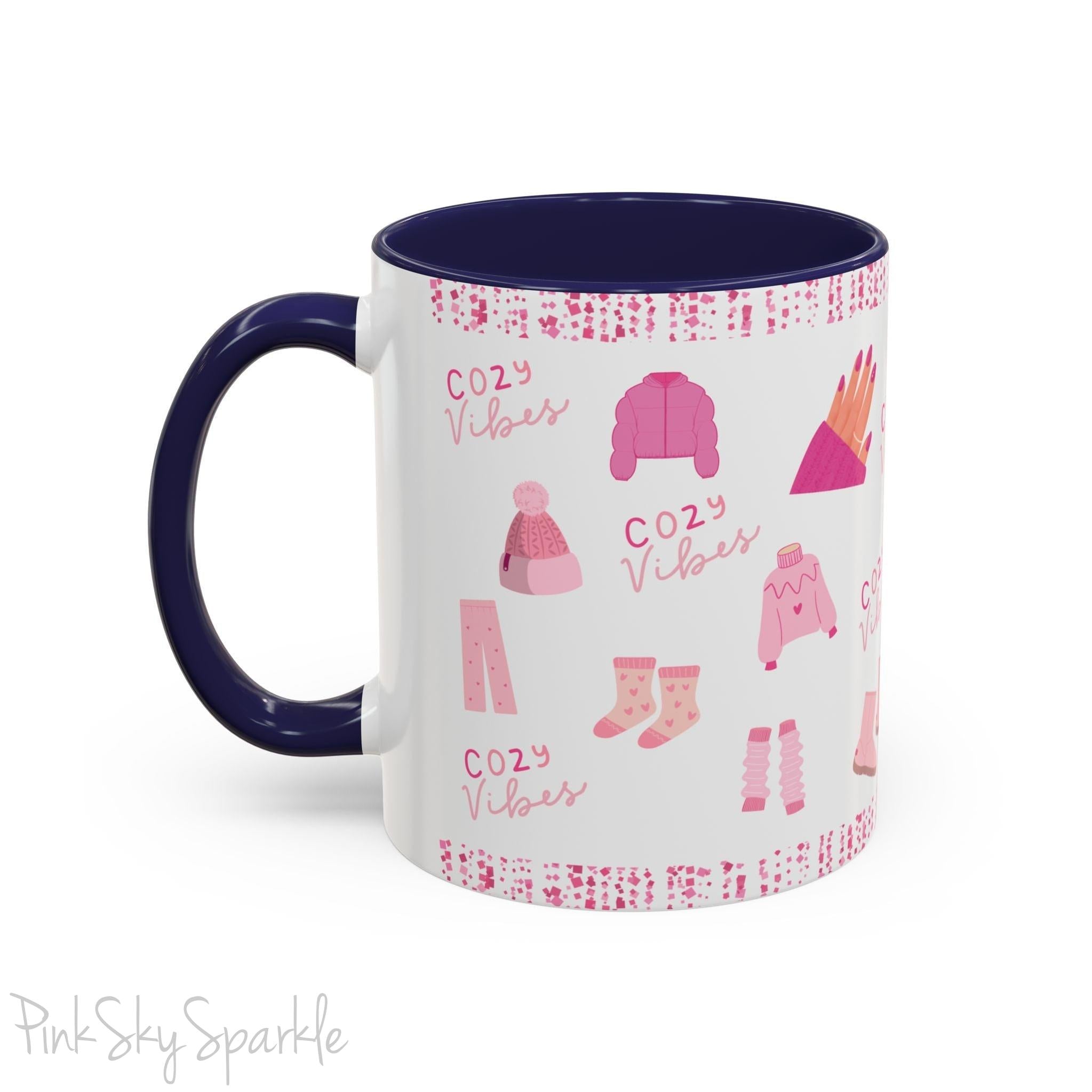 Pink Cozy Vibes Mug - Perfect for coffee, tea, or hot cocoa lovers! This ceramic mug features 'cozy vibes' in a pink font, surrounded by cute illustrations of pink cozy items such as slippers, mittens, blankets and candles. Ideal for creating a warm, cozy atmosphere, this pink-handled mug (also available in light blue, black and navy) makes a great gift for anyone who loves comfort, style and the color pink.