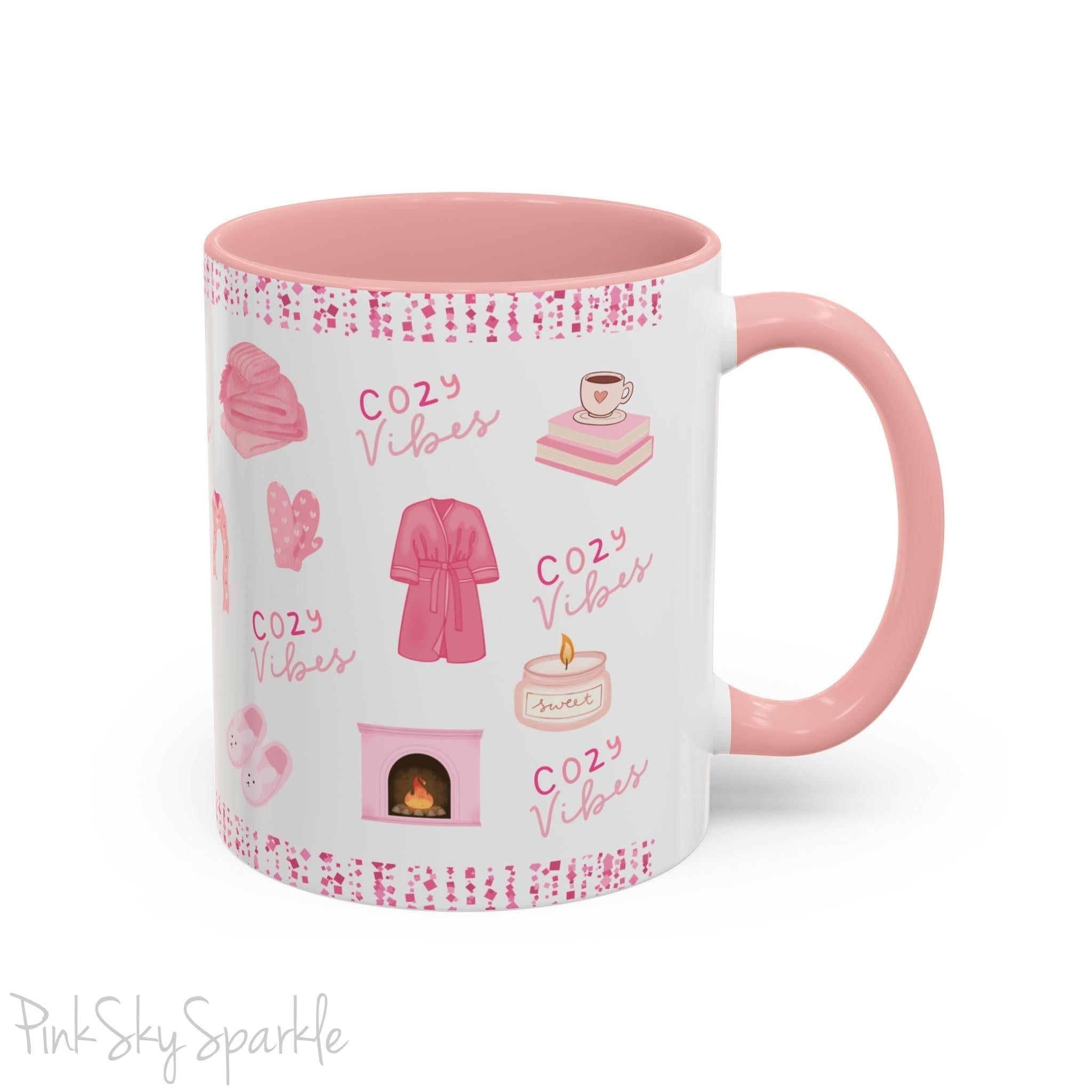 Pink Cozy Vibes Mug - Perfect for coffee, tea, or hot cocoa lovers! This ceramic mug features 'cozy vibes' in a pink font, surrounded by cute illustrations of pink cozy items such as slippers, mittens, blankets and candles. Ideal for creating a warm, cozy atmosphere, this pink-handled mug (also available in light blue, black and navy) makes a great gift for anyone who loves comfort, style and the color pink.