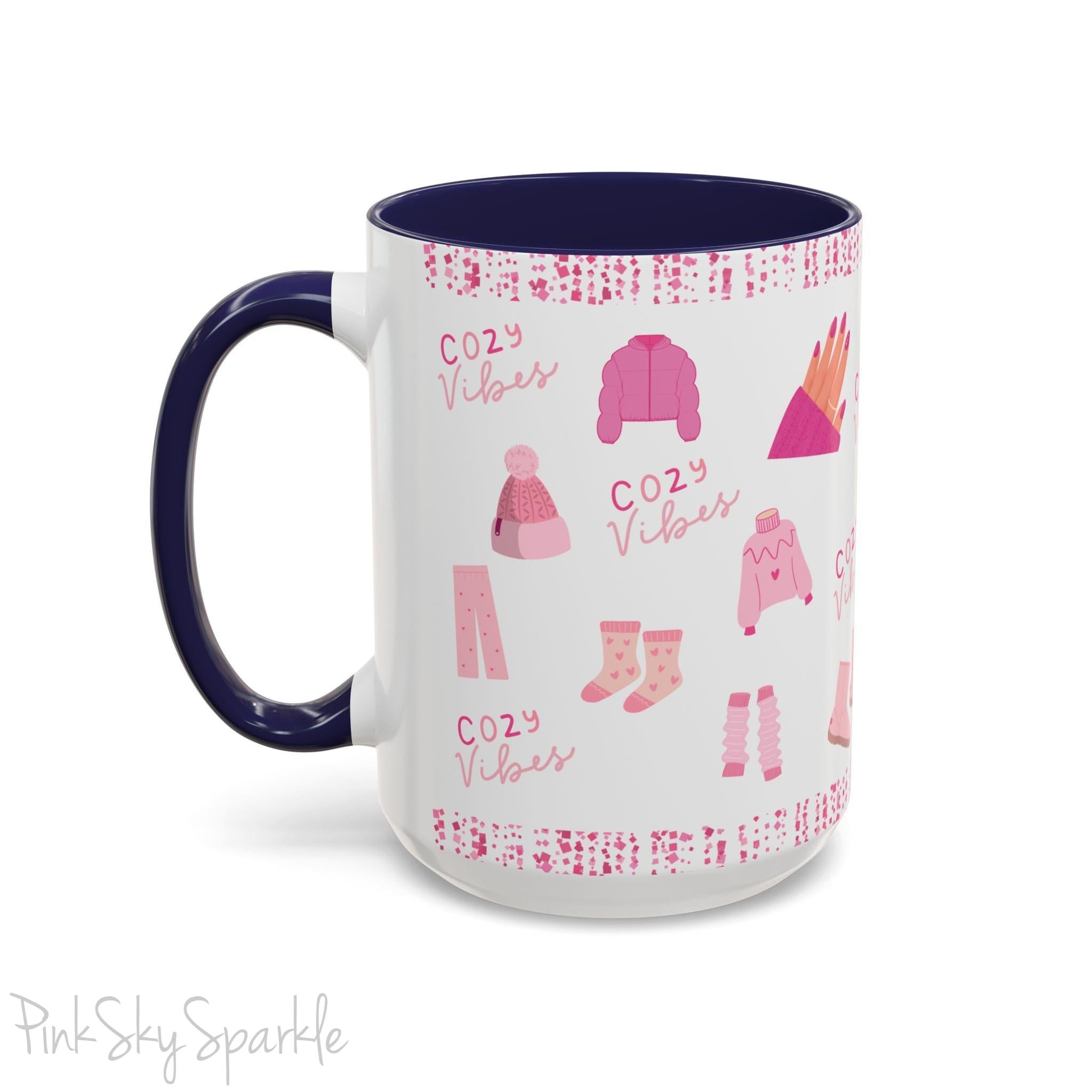 Pink Cozy Vibes Mug - Perfect for coffee, tea, or hot cocoa lovers! This ceramic mug features 'cozy vibes' in a pink font, surrounded by cute illustrations of pink cozy items such as slippers, mittens, blankets and candles. Ideal for creating a warm, cozy atmosphere, this pink-handled mug (also available in light blue, black and navy) makes a great gift for anyone who loves comfort, style and the color pink.