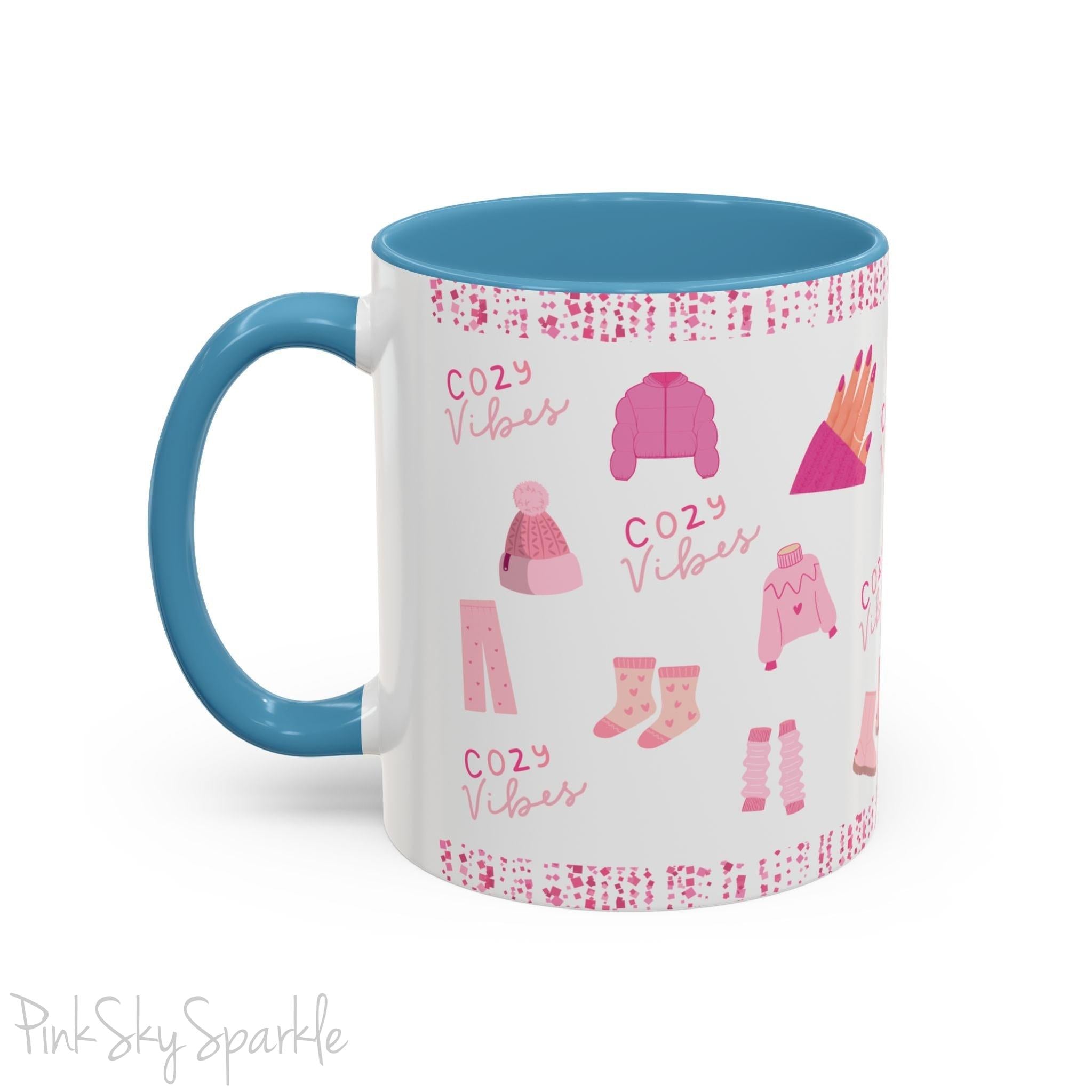 Pink Cozy Vibes Mug - Perfect for coffee, tea, or hot cocoa lovers! This ceramic mug features 'cozy vibes' in a pink font, surrounded by cute illustrations of pink cozy items such as slippers, mittens, blankets and candles. Ideal for creating a warm, cozy atmosphere, this pink-handled mug (also available in light blue, black and navy) makes a great gift for anyone who loves comfort, style and the color pink.