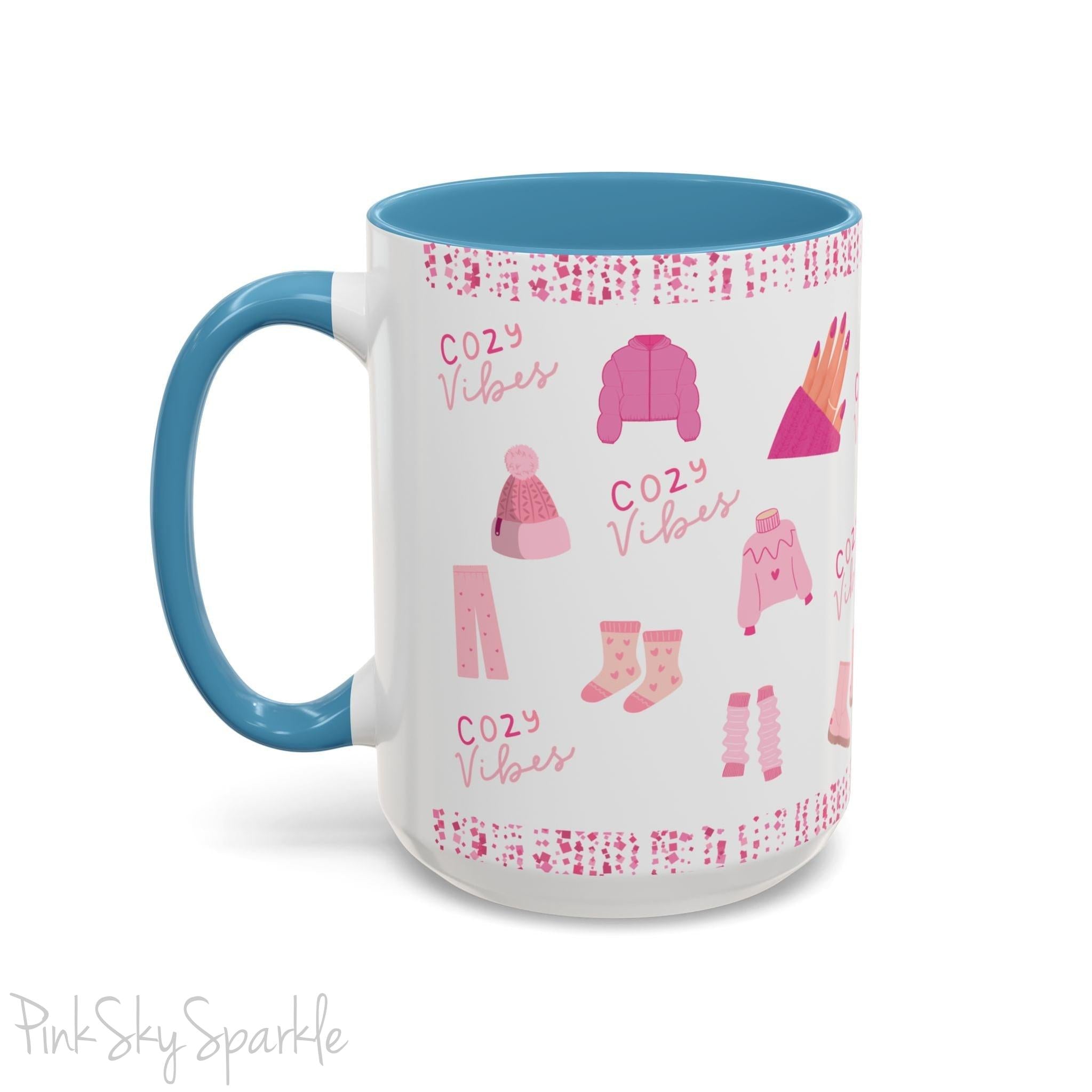 Pink Cozy Vibes Mug - Perfect for coffee, tea, or hot cocoa lovers! This ceramic mug features 'cozy vibes' in a pink font, surrounded by cute illustrations of pink cozy items such as slippers, mittens, blankets and candles. Ideal for creating a warm, cozy atmosphere, this pink-handled mug (also available in light blue, black and navy) makes a great gift for anyone who loves comfort, style and the color pink.