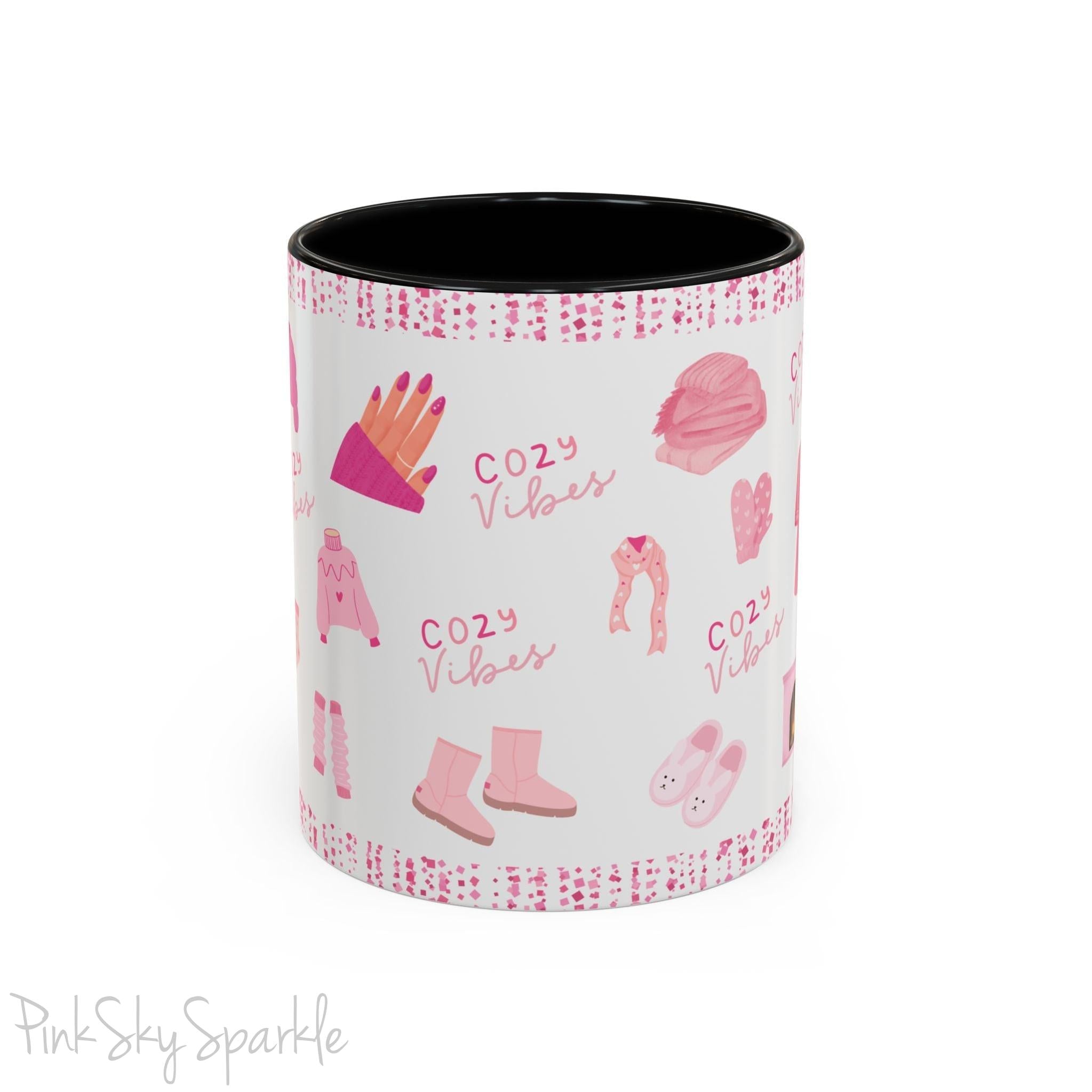 Pink Cozy Vibes Mug - Perfect for coffee, tea, or hot cocoa lovers! This ceramic mug features 'cozy vibes' in a pink font, surrounded by cute illustrations of pink cozy items such as slippers, mittens, blankets and candles. Ideal for creating a warm, cozy atmosphere, this pink-handled mug (also available in light blue, black and navy) makes a great gift for anyone who loves comfort, style and the color pink.