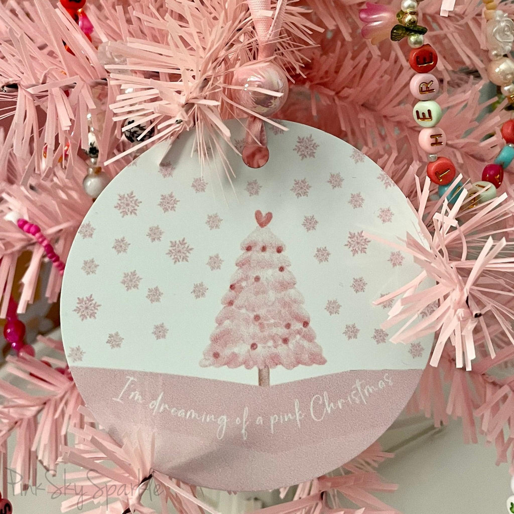 A pink Christmas tree ornament with soft pastel tones and elegant design, featuring the phrase "I'm Dreaming of a Pink Christmas." Perfect for adding a whimsical touch to holiday decor.