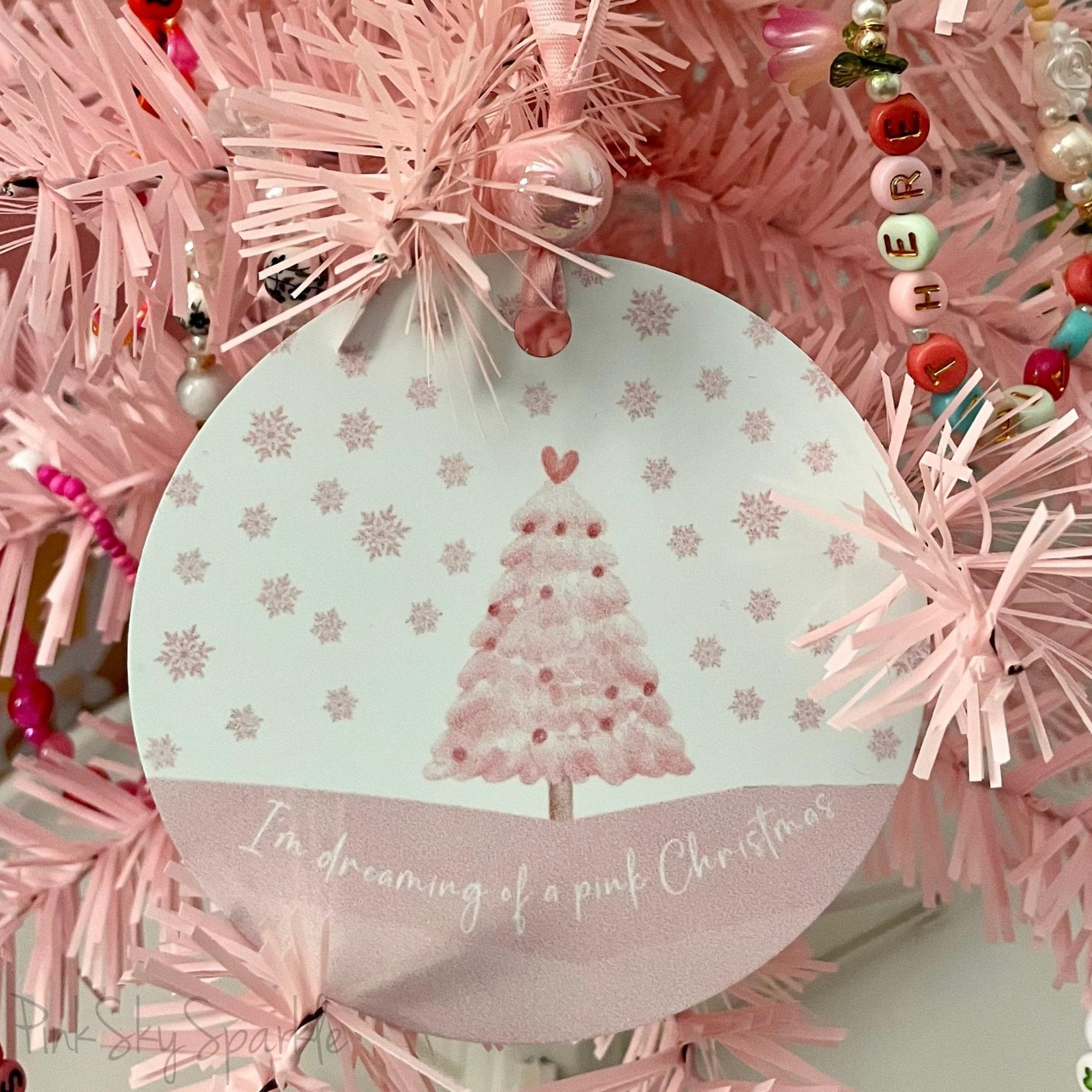 A pink Christmas tree ornament with soft pastel tones and elegant design, featuring the phrase "I'm Dreaming of a Pink Christmas." Perfect for adding a whimsical touch to holiday decor.