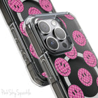 Clear magnetic phone case featuring pink checkered smiley faces on a transparent background, designed for MagSafe® compatibility with air-cushioned bumper corners.