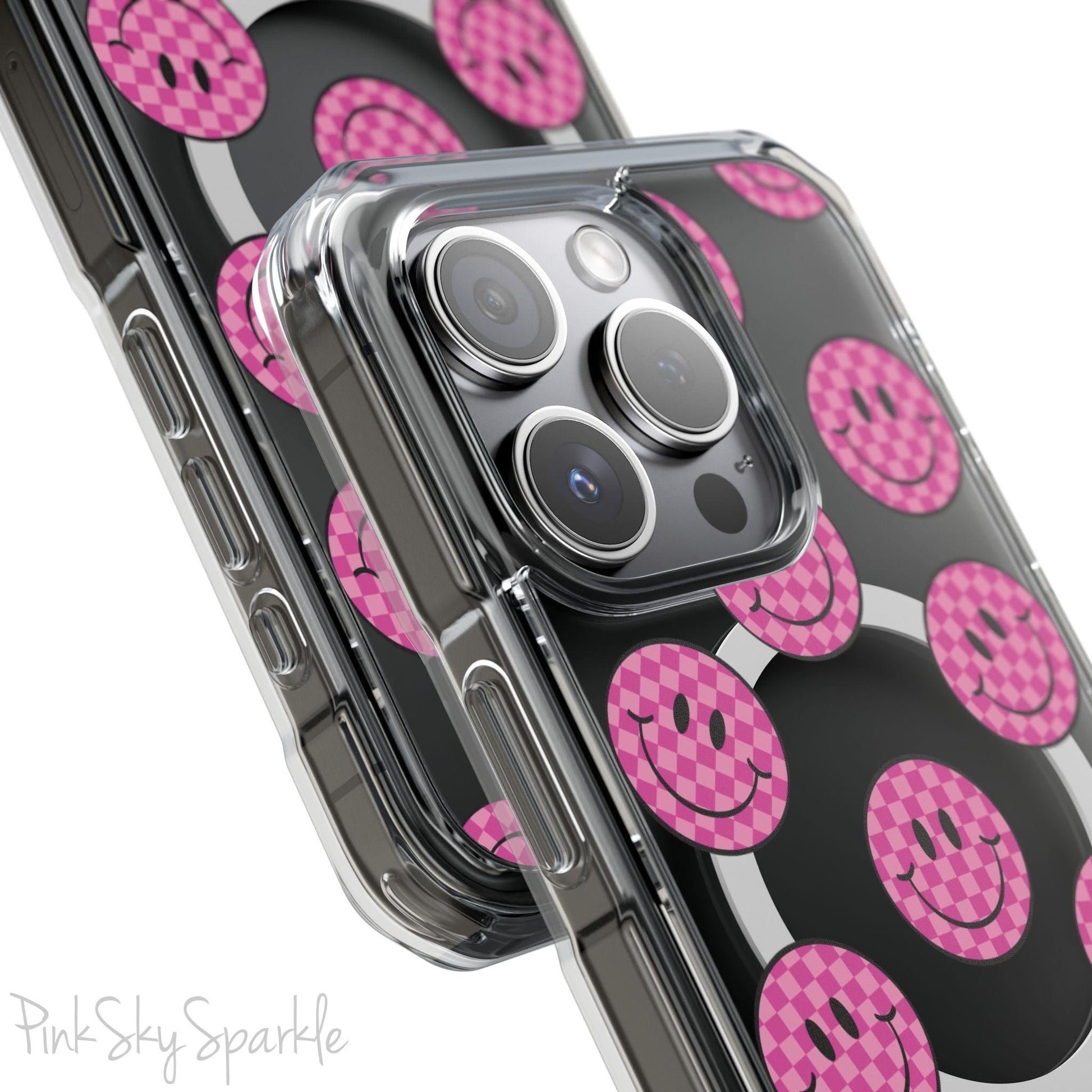 Clear magnetic phone case featuring pink checkered smiley faces on a transparent background, designed for MagSafe® compatibility with air-cushioned bumper corners.