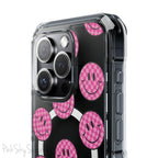 Clear magnetic phone case featuring pink checkered smiley faces on a transparent background, designed for MagSafe® compatibility with air-cushioned bumper corners.