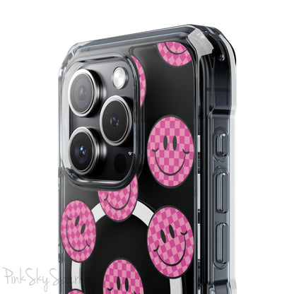 Clear magnetic phone case featuring pink checkered smiley faces on a transparent background, designed for MagSafe® compatibility with air-cushioned bumper corners.