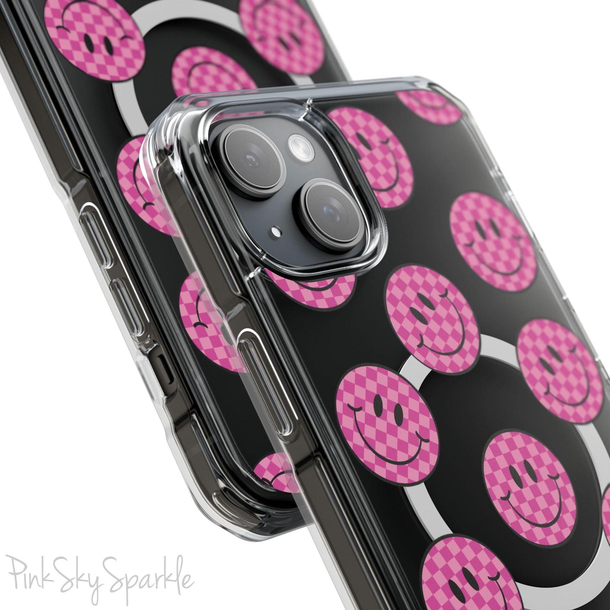 Clear magnetic phone case featuring pink checkered smiley faces on a transparent background, designed for MagSafe® compatibility with air-cushioned bumper corners.