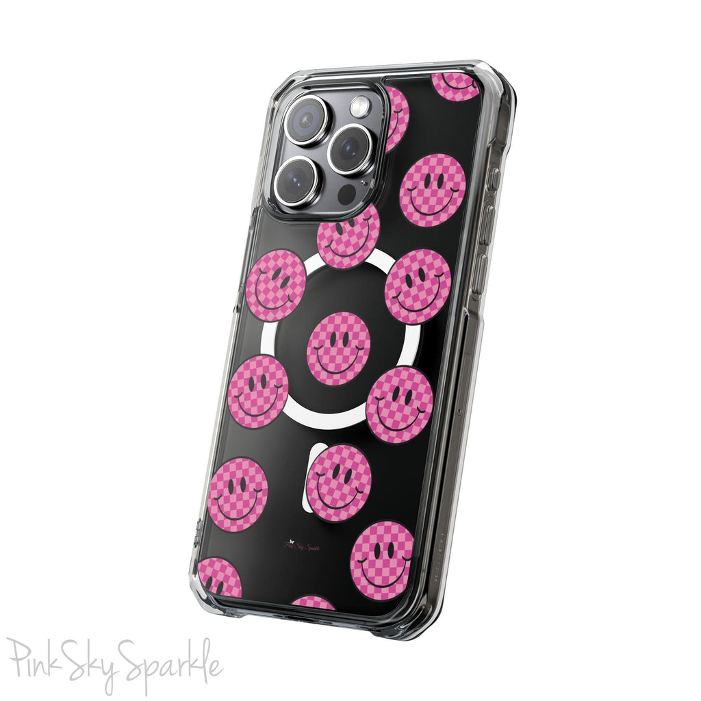 Clear magnetic phone case featuring pink checkered smiley faces on a transparent background, designed for MagSafe® compatibility with air-cushioned bumper corners.