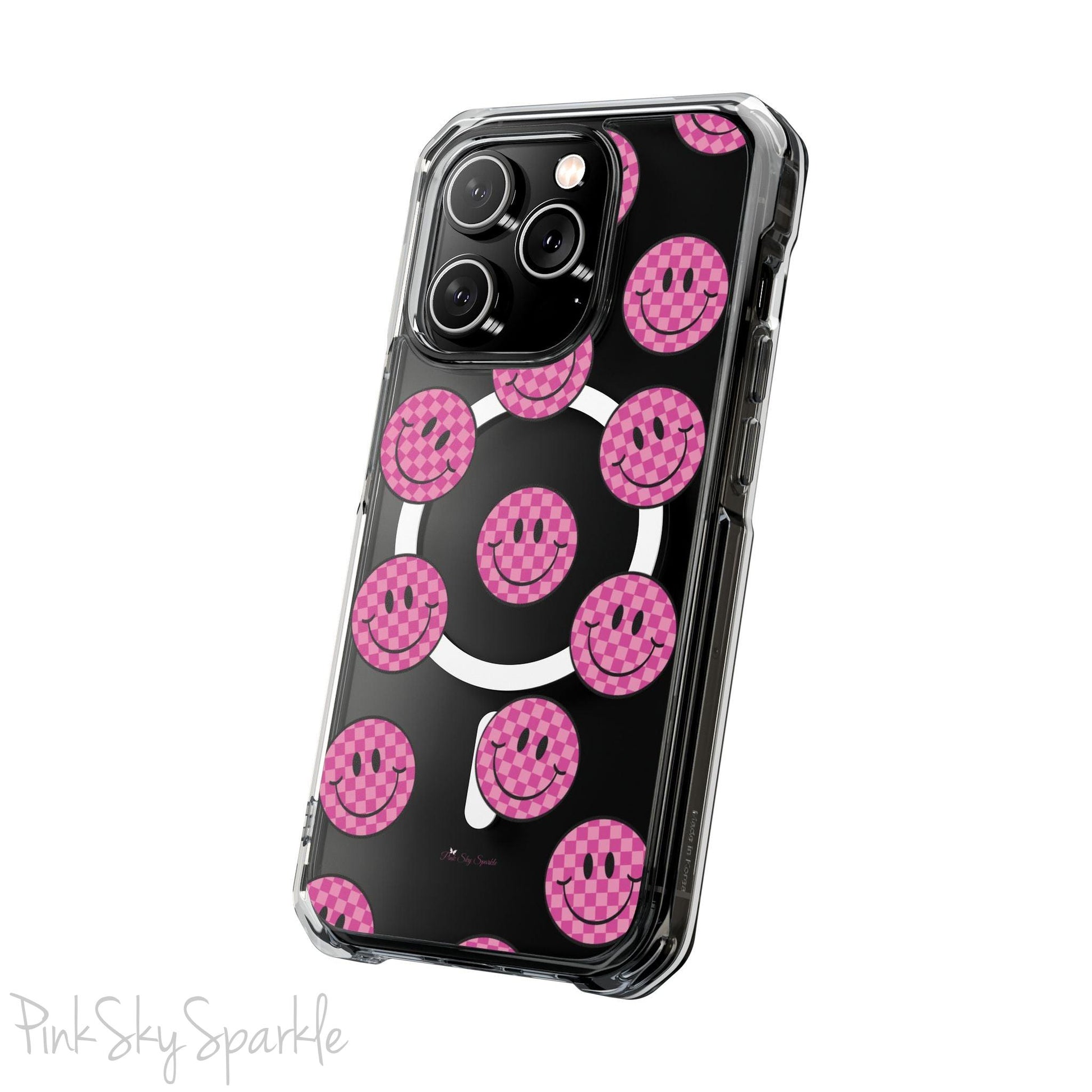 Clear magnetic phone case featuring pink checkered smiley faces on a transparent background, designed for MagSafe® compatibility with air-cushioned bumper corners.