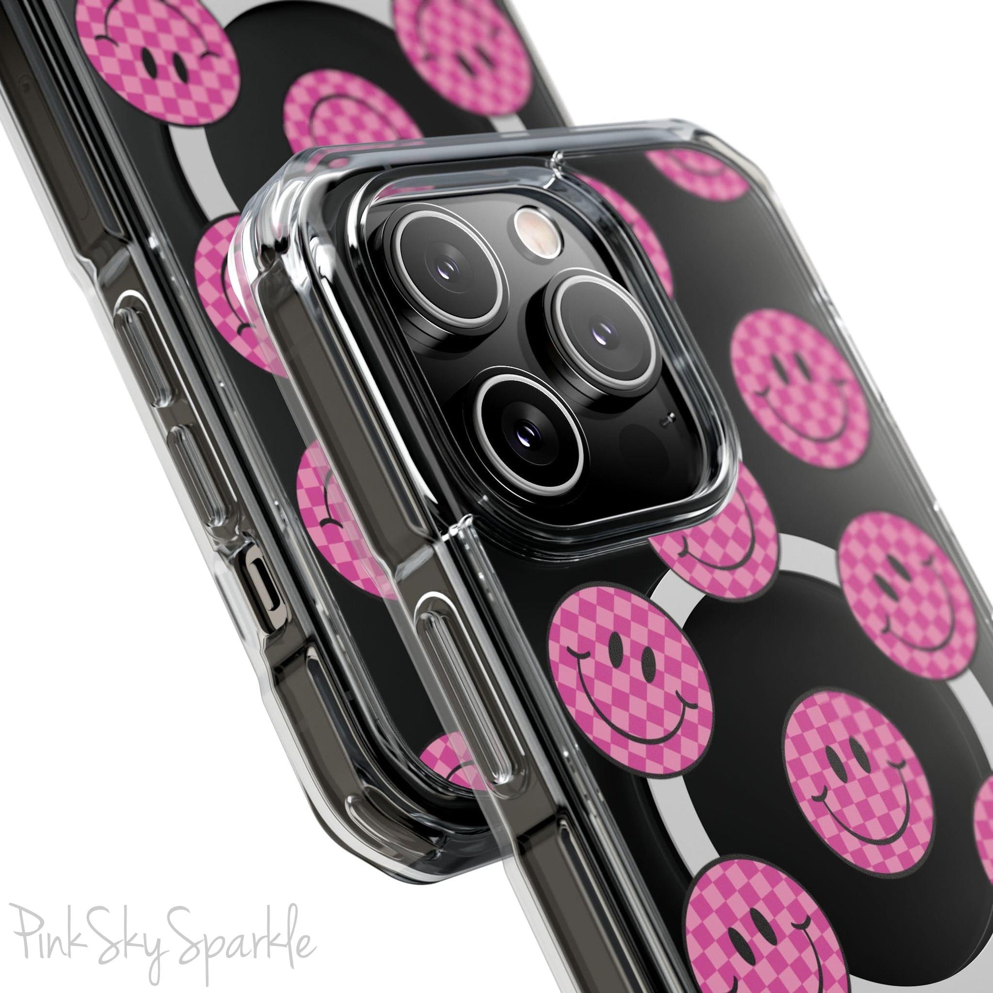 Clear magnetic phone case featuring pink checkered smiley faces on a transparent background, designed for MagSafe® compatibility with air-cushioned bumper corners.