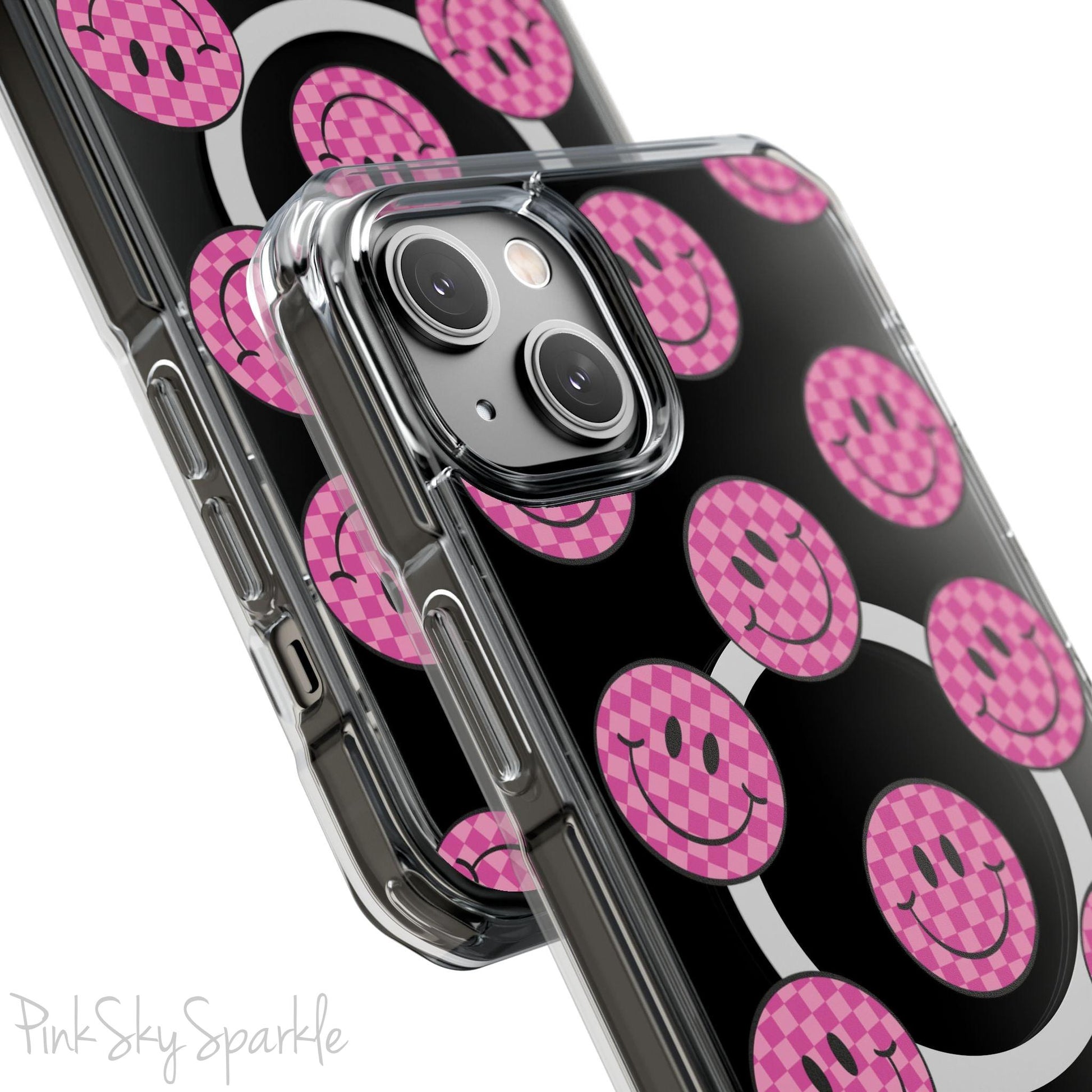 Clear magnetic phone case featuring pink checkered smiley faces on a transparent background, designed for MagSafe® compatibility with air-cushioned bumper corners.