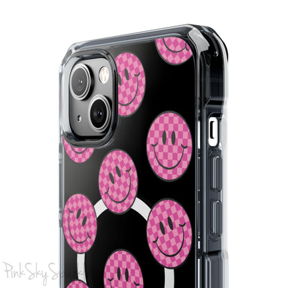 Clear magnetic phone case featuring pink checkered smiley faces on a transparent background, designed for MagSafe® compatibility with air-cushioned bumper corners.