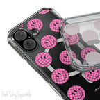 Clear magnetic phone case featuring pink checkered smiley faces on a transparent background, designed for MagSafe® compatibility with air-cushioned bumper corners.