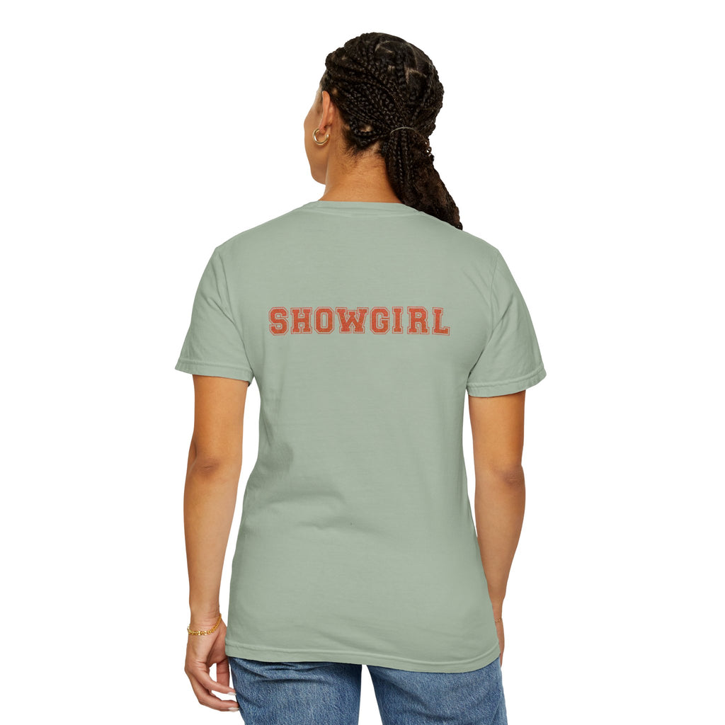 Person wearing a light green t-shirt with 'SHOWGIRL' printed on the back, standing against a white background.