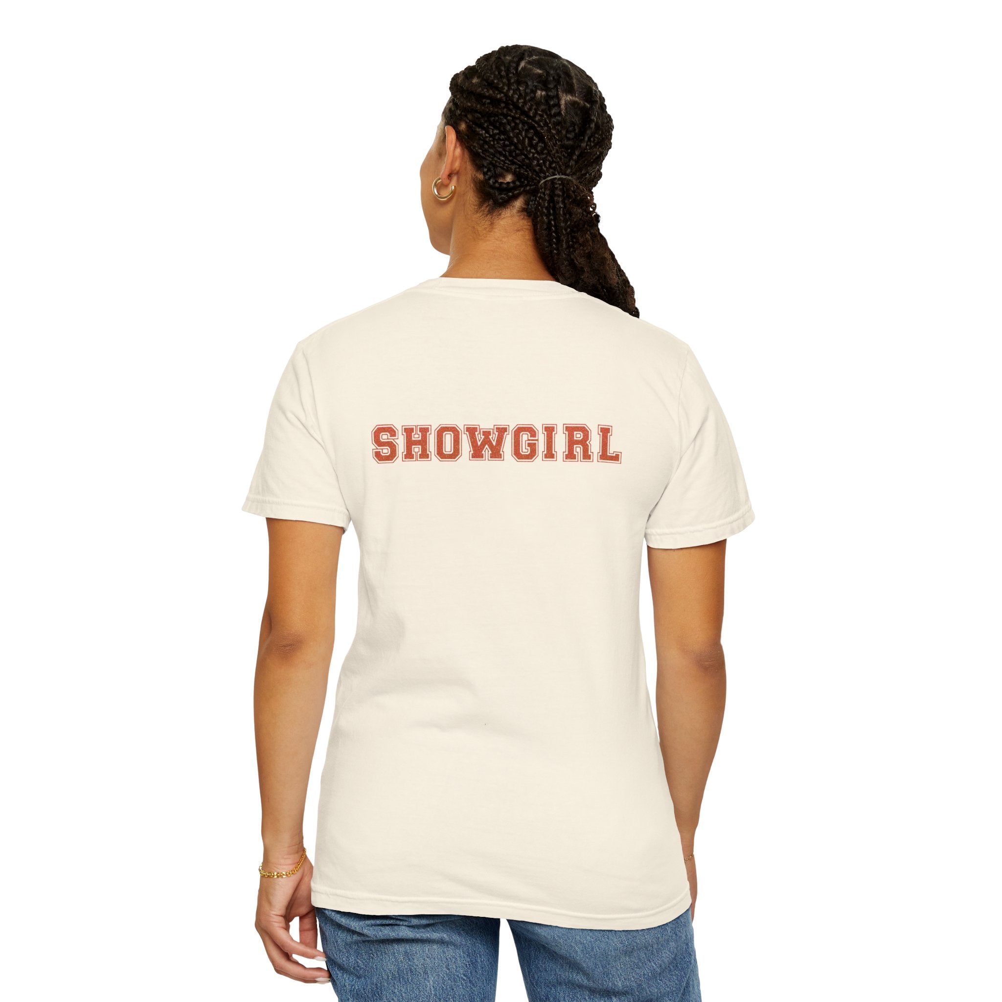 Person wearing an ivory colored t-shirt with 'SHOWGIRL' printed on the back against a white background