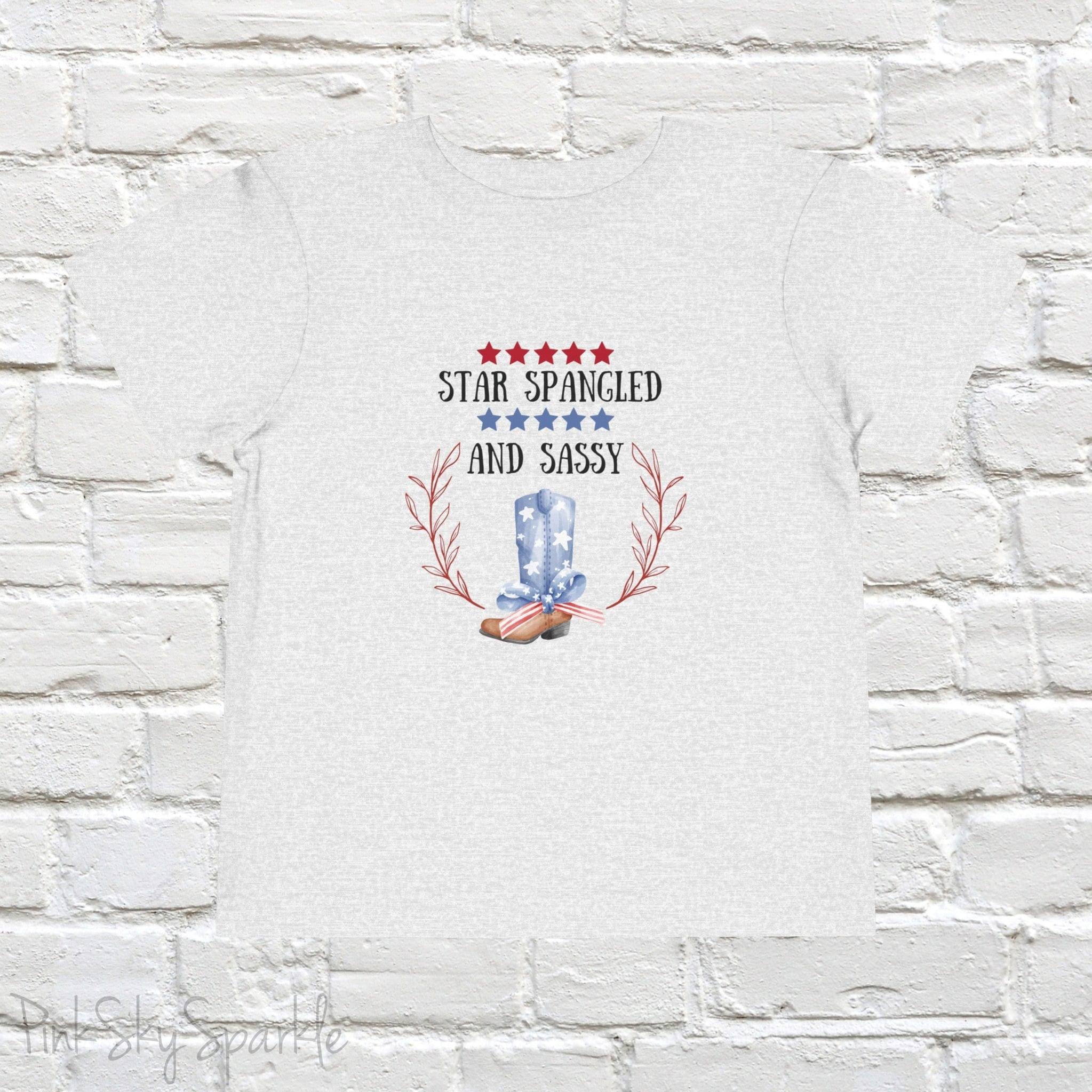 Dress your little one in patriotic style with our adorable toddler t-shirt, perfect for the 4th of July! This charming tee features the playful phrase "Star Spangled and Sassy" alongside a cute graphic of a red, white, and blue cowgirl boot adorned with a bow.