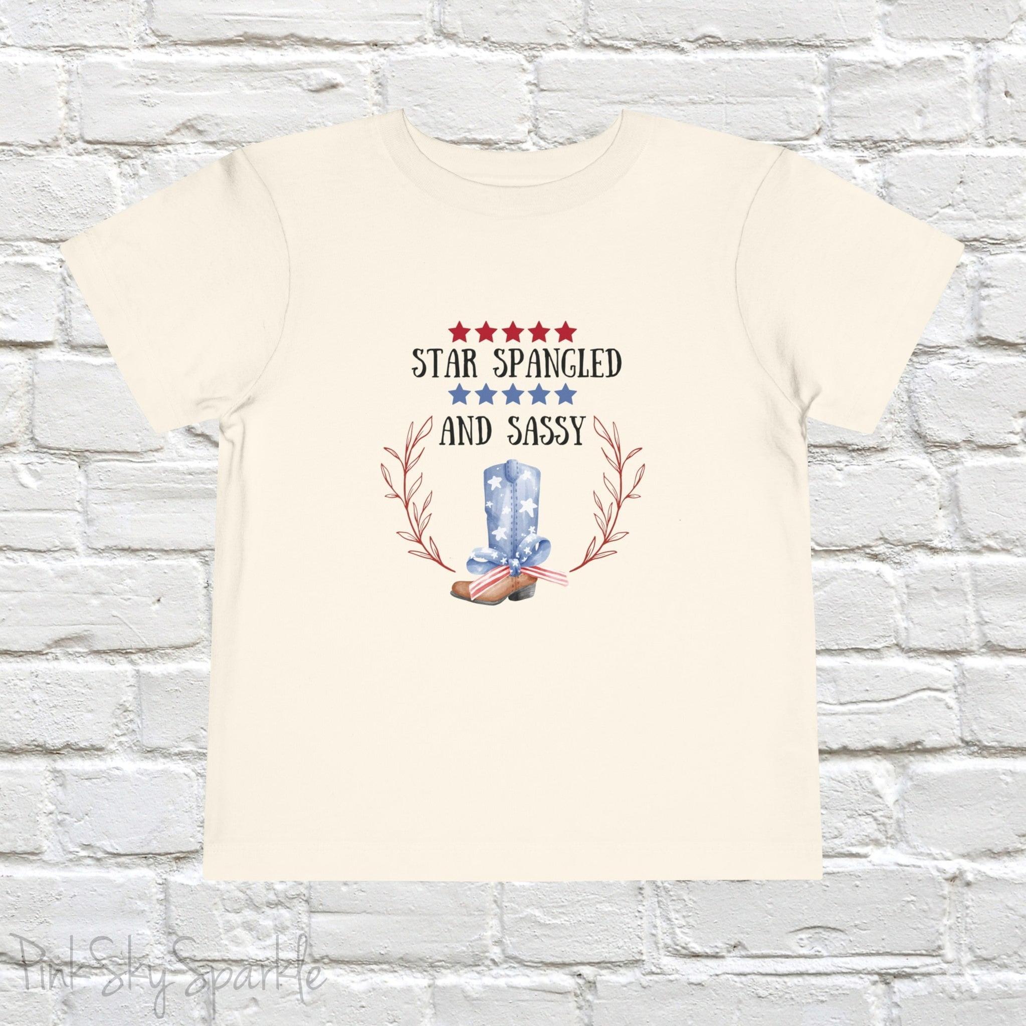Dress your little one in patriotic style with our adorable toddler t-shirt, perfect for the 4th of July! This charming tee features the playful phrase "Star Spangled and Sassy" alongside a cute graphic of a red, white, and blue cowgirl boot adorned with a bow.