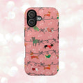 iPhone case with holiday dogs in sweaters on pink background.