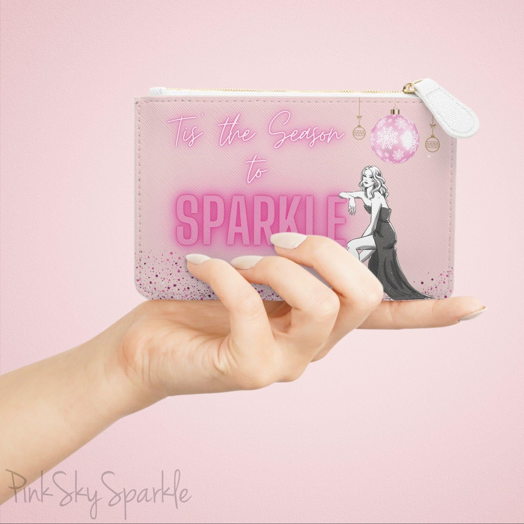 Hand holding the pink sparkle-themed mini clutch bag against a soft pink background.
