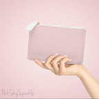Hand holding the plain pink back of the mini clutch bag against a soft pink background.