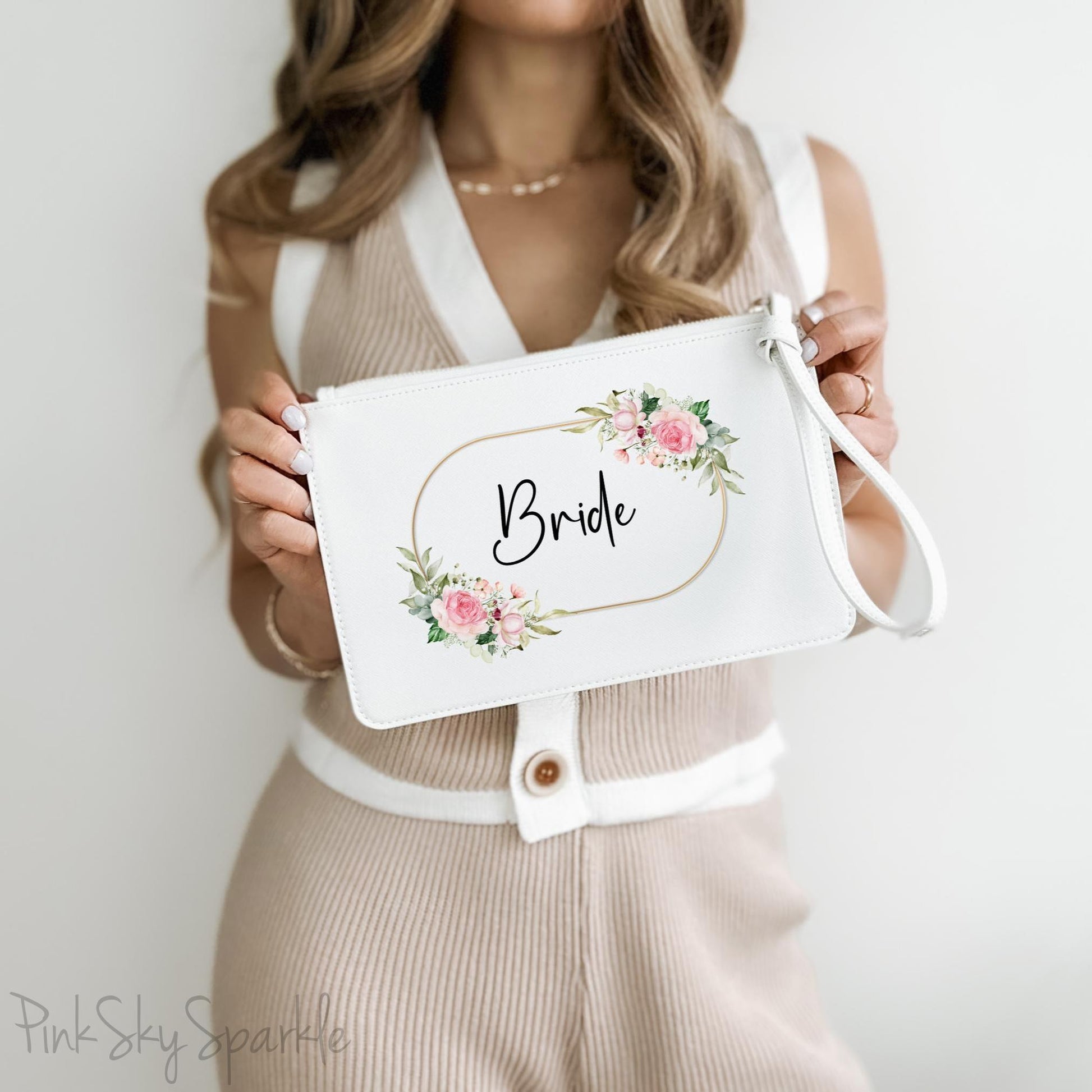 White clutch wristlet bag with a gold, pink and green floral design and the word Bride in a fancy font black font in the centre. 