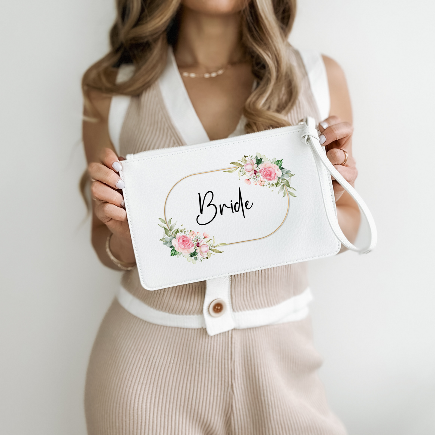 White clutch wristlet bag with a gold, pink and green floral design and the word Bride in a fancy font black font in the centre. 