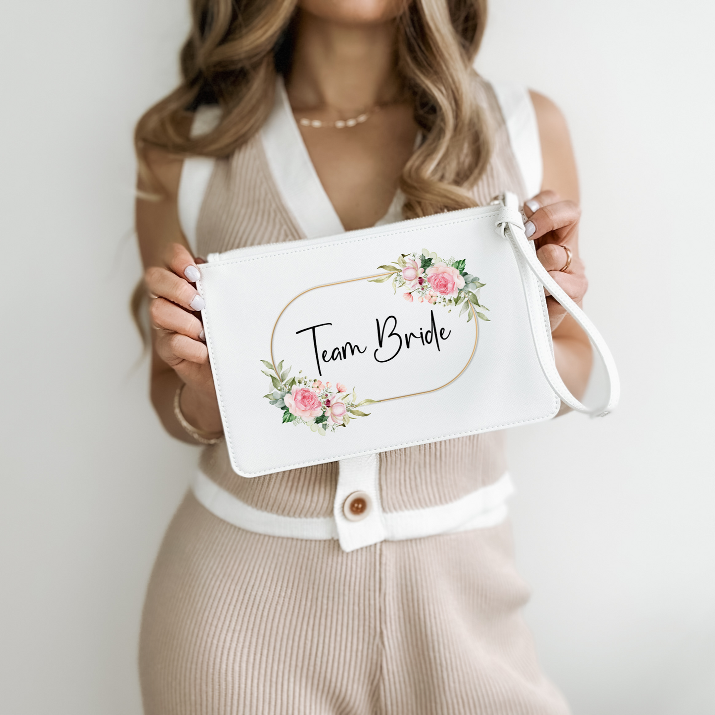 White clutch wristlet bag with a gold, pink and green floral circular design with the words Team Bride written in a black fancy font in the centre. 