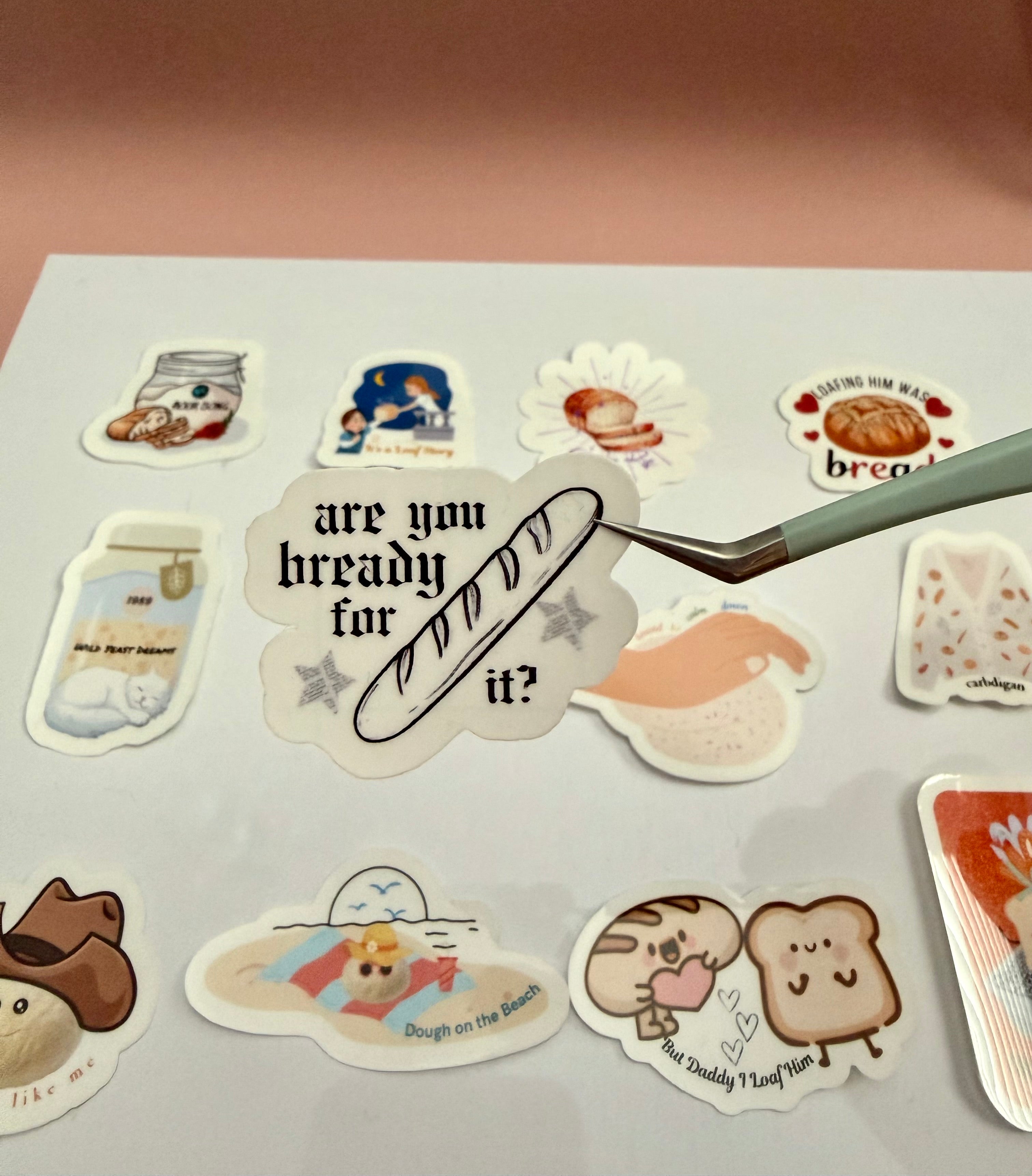 Sticker with a baguette and stars with newspaper print design that says 'are you bready for it?' 