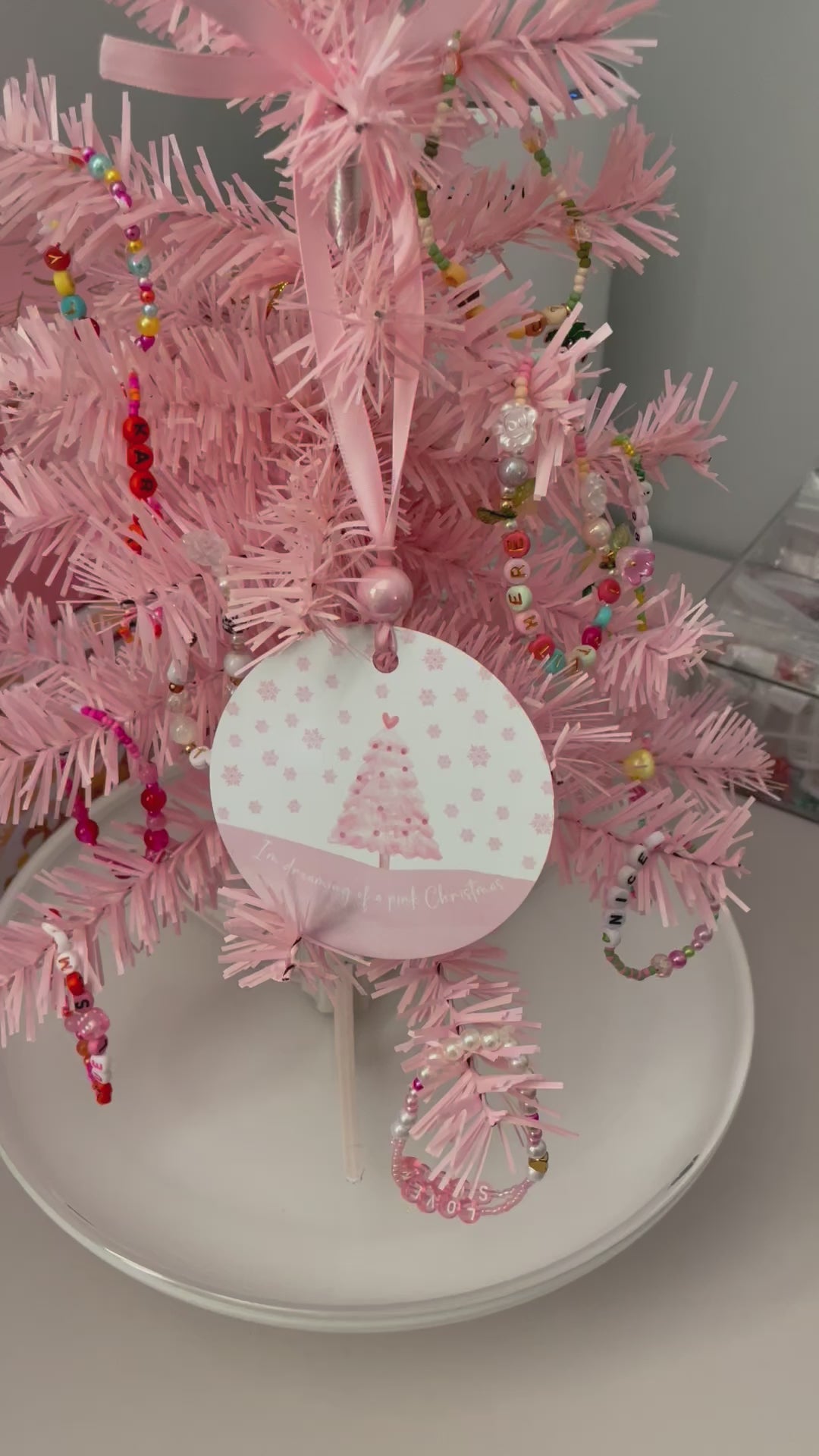 A pink Christmas tree ornament with soft pastel tones and elegant design, featuring the phrase "I'm Dreaming of a Pink Christmas." Perfect for adding a whimsical touch to holiday decor.